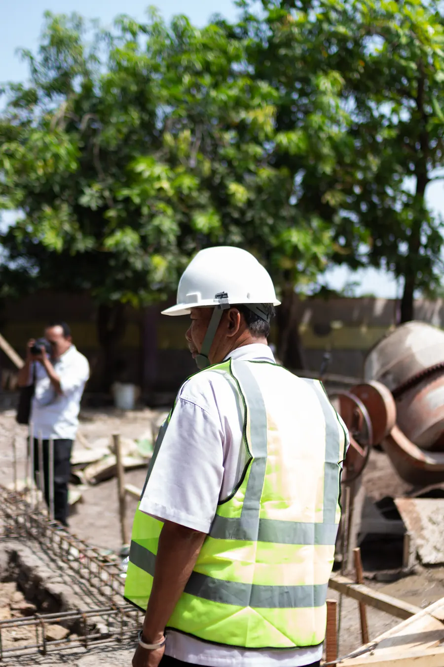 Técnico de obra con casco y chaleco reflectante supervisando una construcción